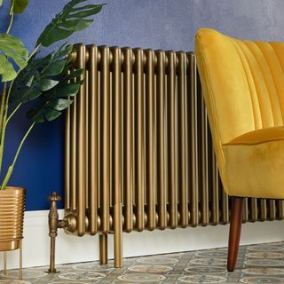 Gold metal radiator next to blue wall and yellow chair