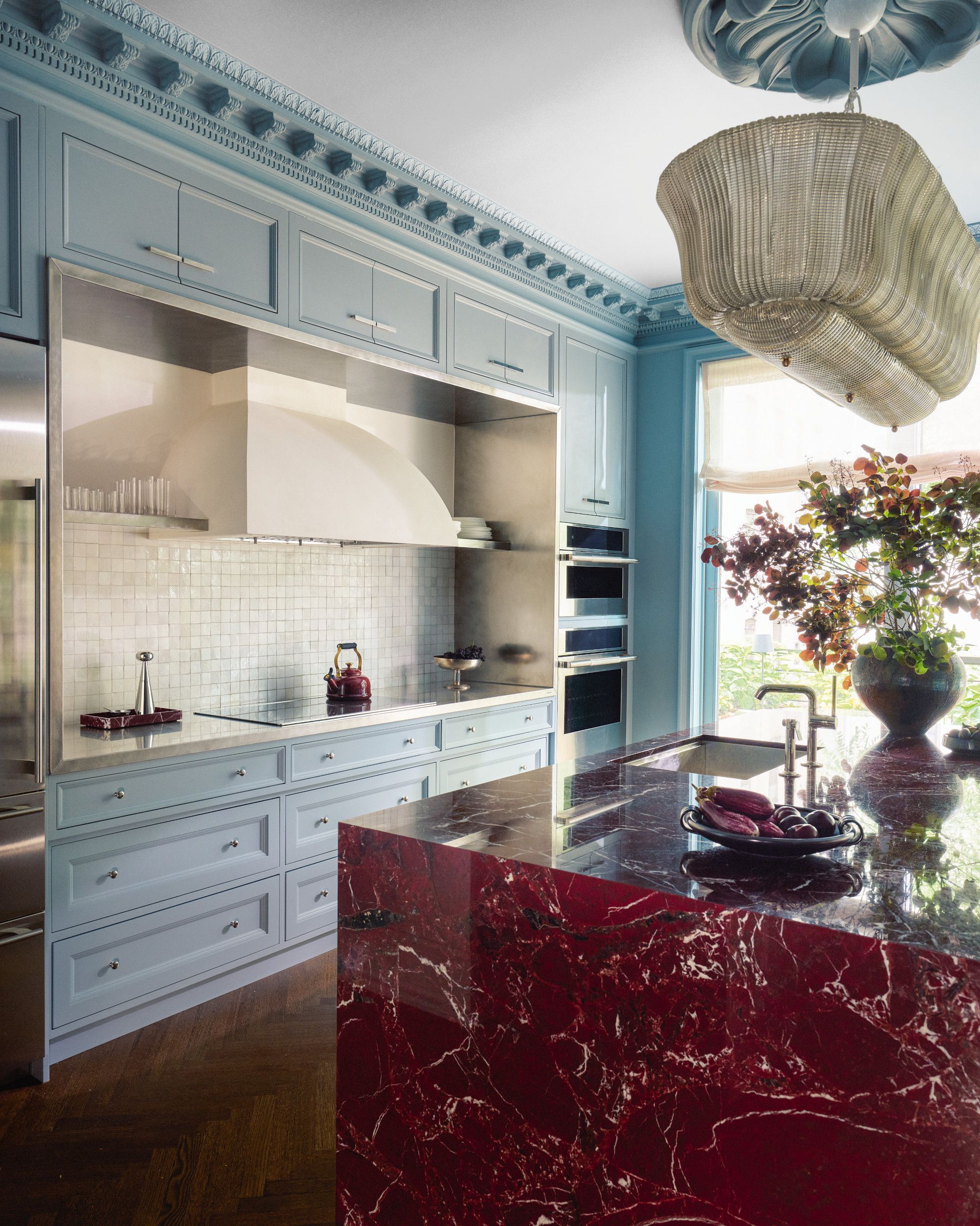 Blue kitchen with burgundy marble island, glass pendant light and wood floor