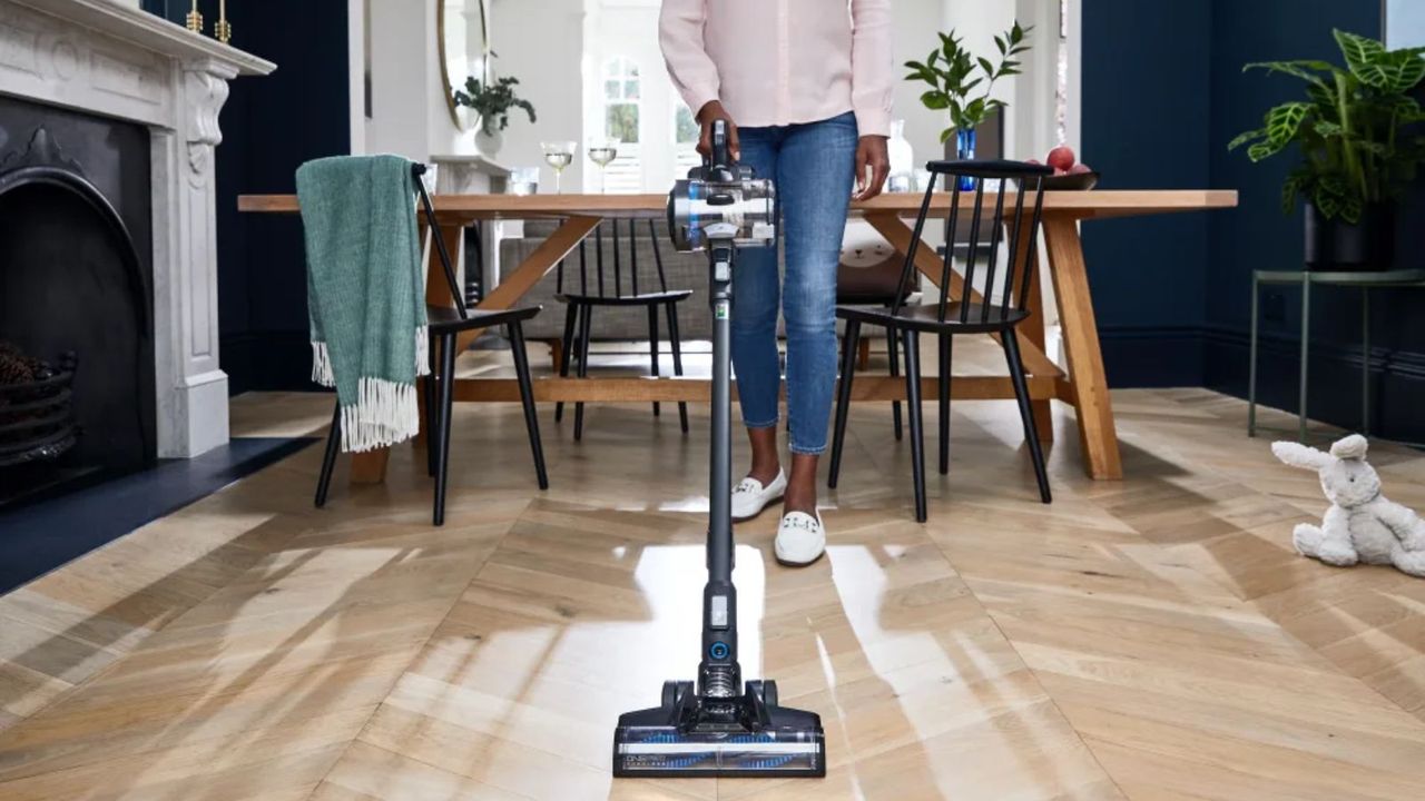 The Hoover ONEPWR Blade+ at use on wooden floor, being pushed by a woman