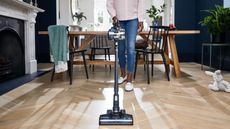 The Hoover Blade+ at use on wooden floor, being pushed by a woman