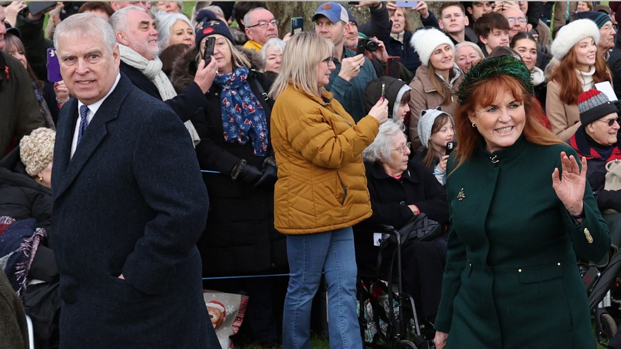 Prince Andrew and Sarah Ferguson smiling and walking to church on Christmas waving to crowds with people gathered behind them