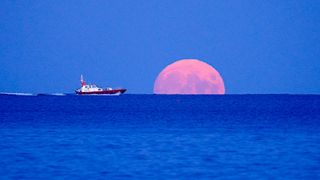 A pilot boat passes the rising Harvest Moon on September 20, 2021 off Swanpool Beach, Falmouth, England.