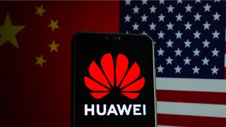Huawei logo on a smartphone and flags of China and US on the blurred background