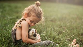 Adopt a guinea pig. Young girl cuddling a guinea pig