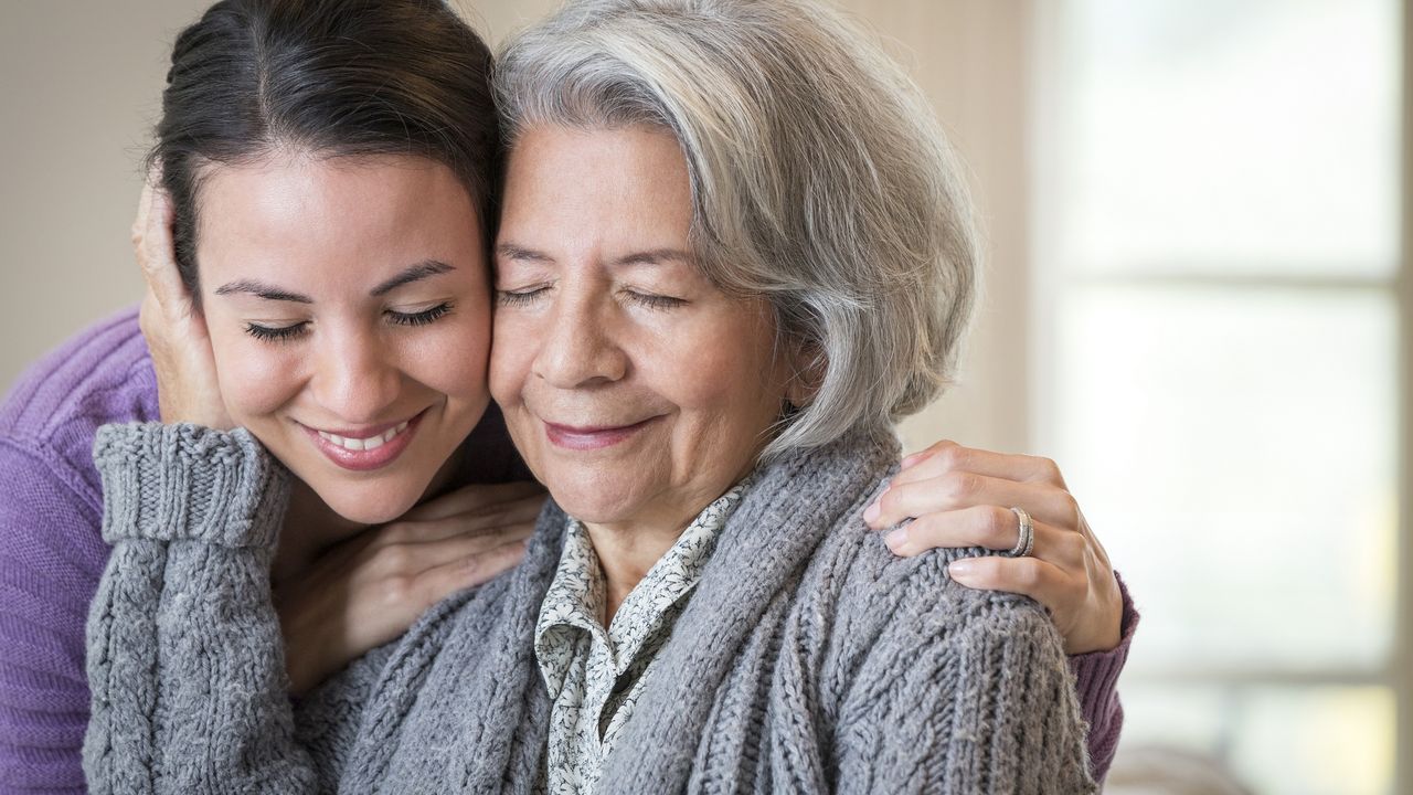 An adult daughter hugs her mother.