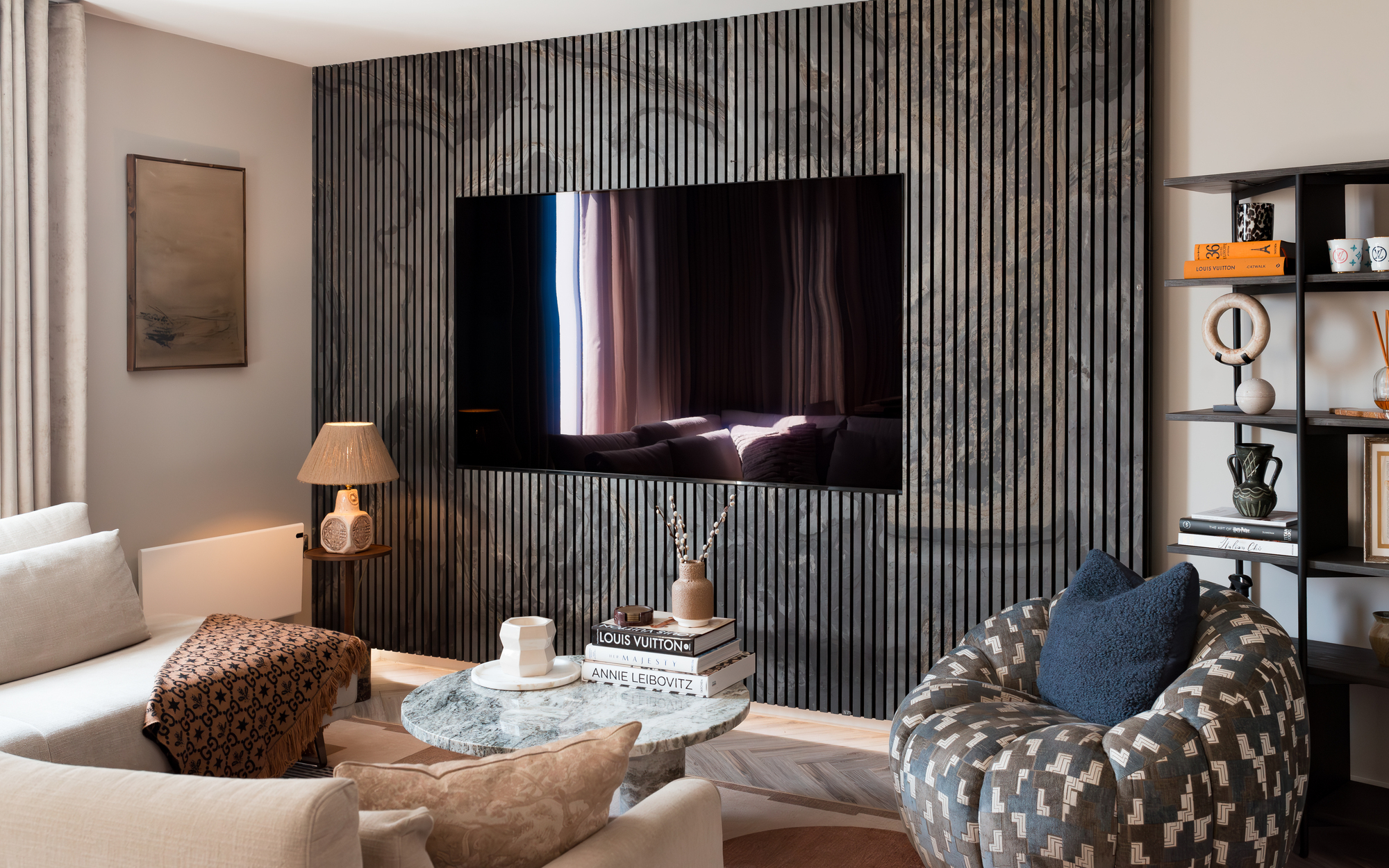 A small living room with a wood slat wall with a large TV built-in