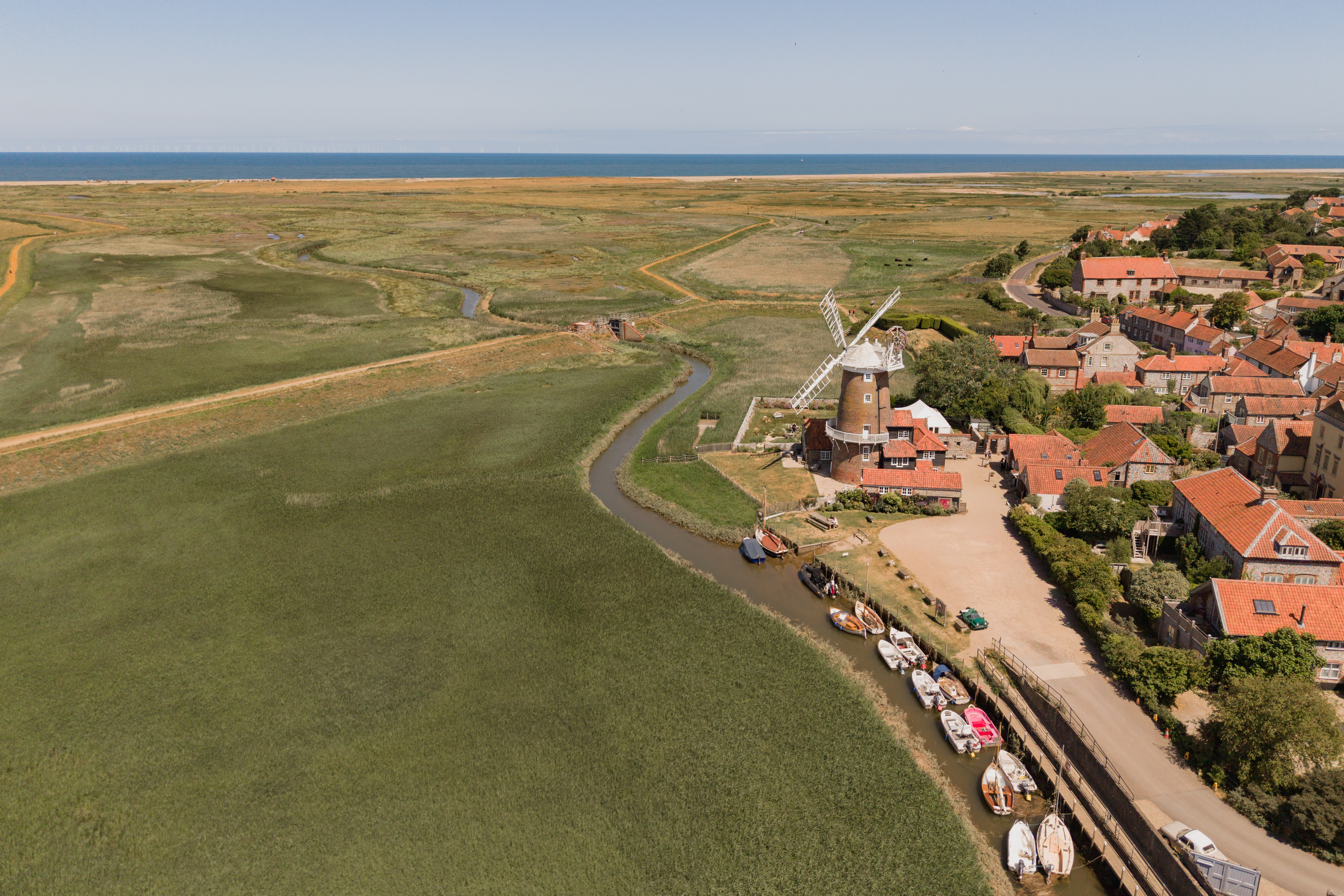 Cley Windmill. The mill is surrounded by reed beds and little rivers, and it is red brick with a white top. Inside, the rooms are luxurious but rustic, with lots of brick and exposed beams.