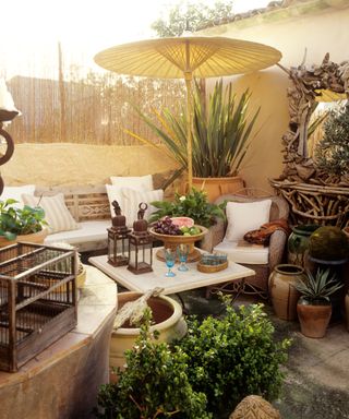 a busy outdoor patio with furniture, umbrella, and pots, and decor on top of the table
