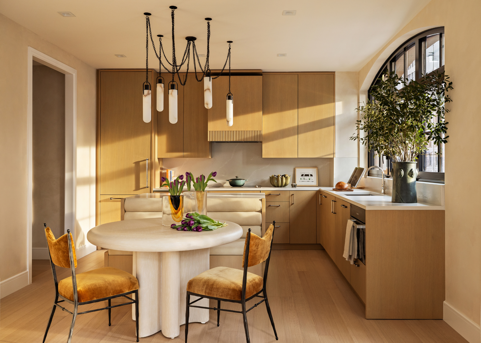 An all wood kitchen with round white table and ochre velvet dining chairs round it