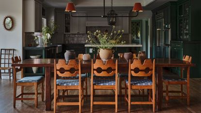 a dining area with vintage swedish pine chairs looking through to an open plan dark green kitchen