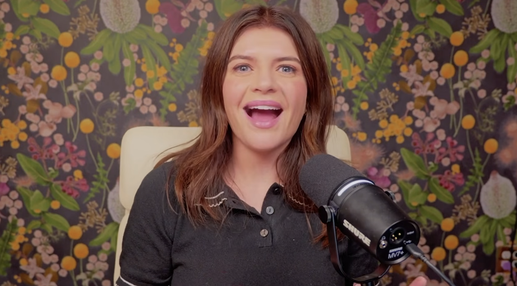 Casey Wilson wearing a polo in front of a mic for Bitch Sesh talking about BravoCon.