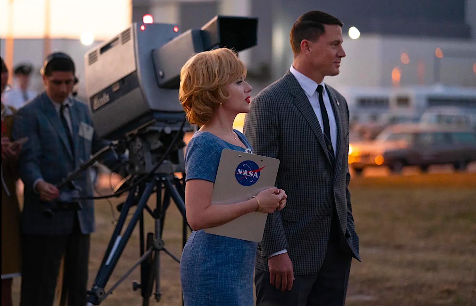 A woman and man stand next to '60s-era TV camera