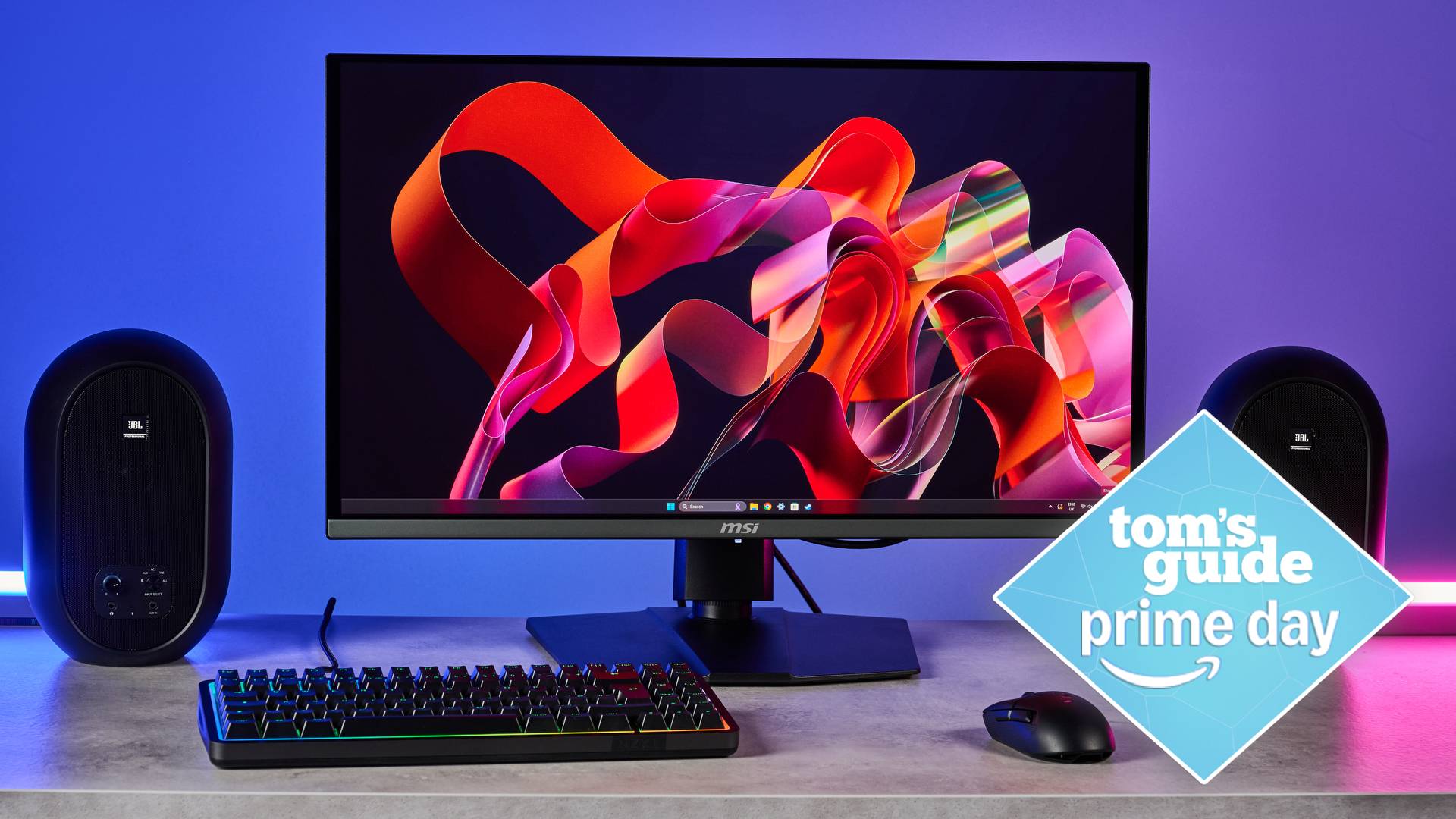 MSI MPG 272URX on table with keyboard and speakers with Tom&#039;s Guide Prime Day badge