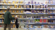 A supermarket shopper with a trolley looks at chilled cabinets of meat