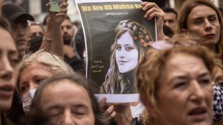 People hold signs and chant slogans during a protest over the death of Iranian Mahsa Amini outside the Iranian Consulate on September 21, 2022 in Istanbul, Turkey.