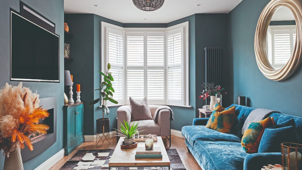 A blue living room with a TV above the fireplace