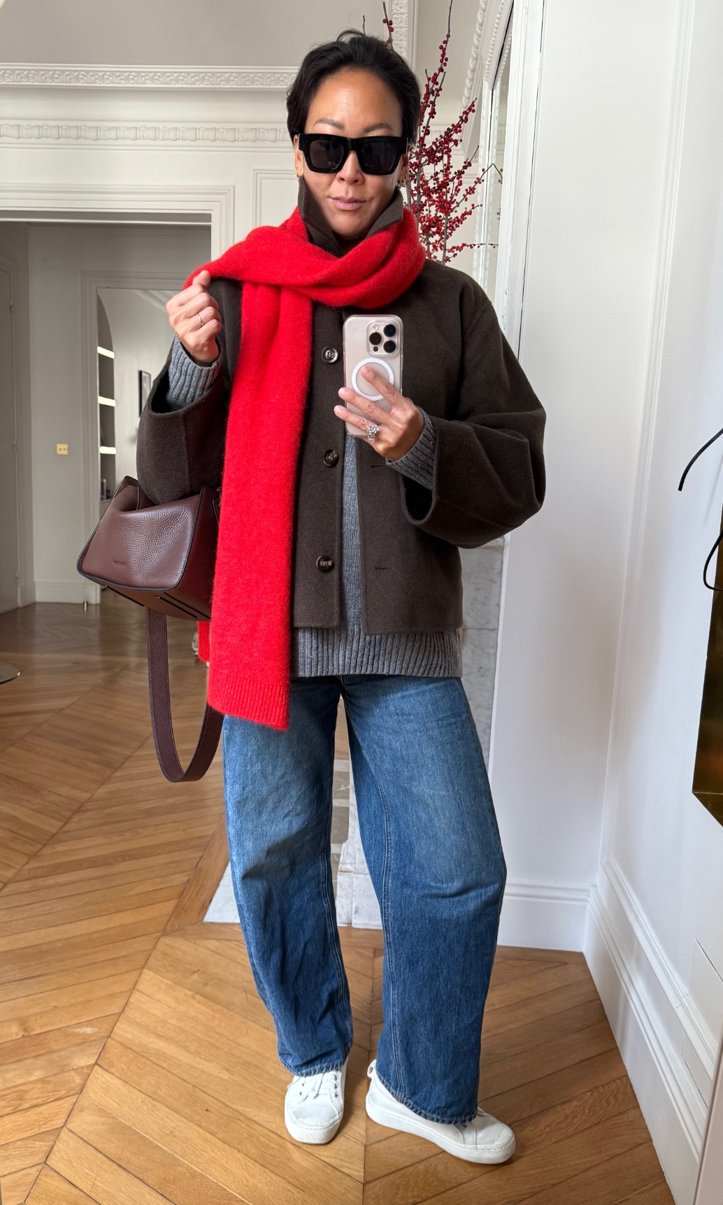 Irene Kim wearing a sweater, a jacket, jeans, sneakers, and a scarf