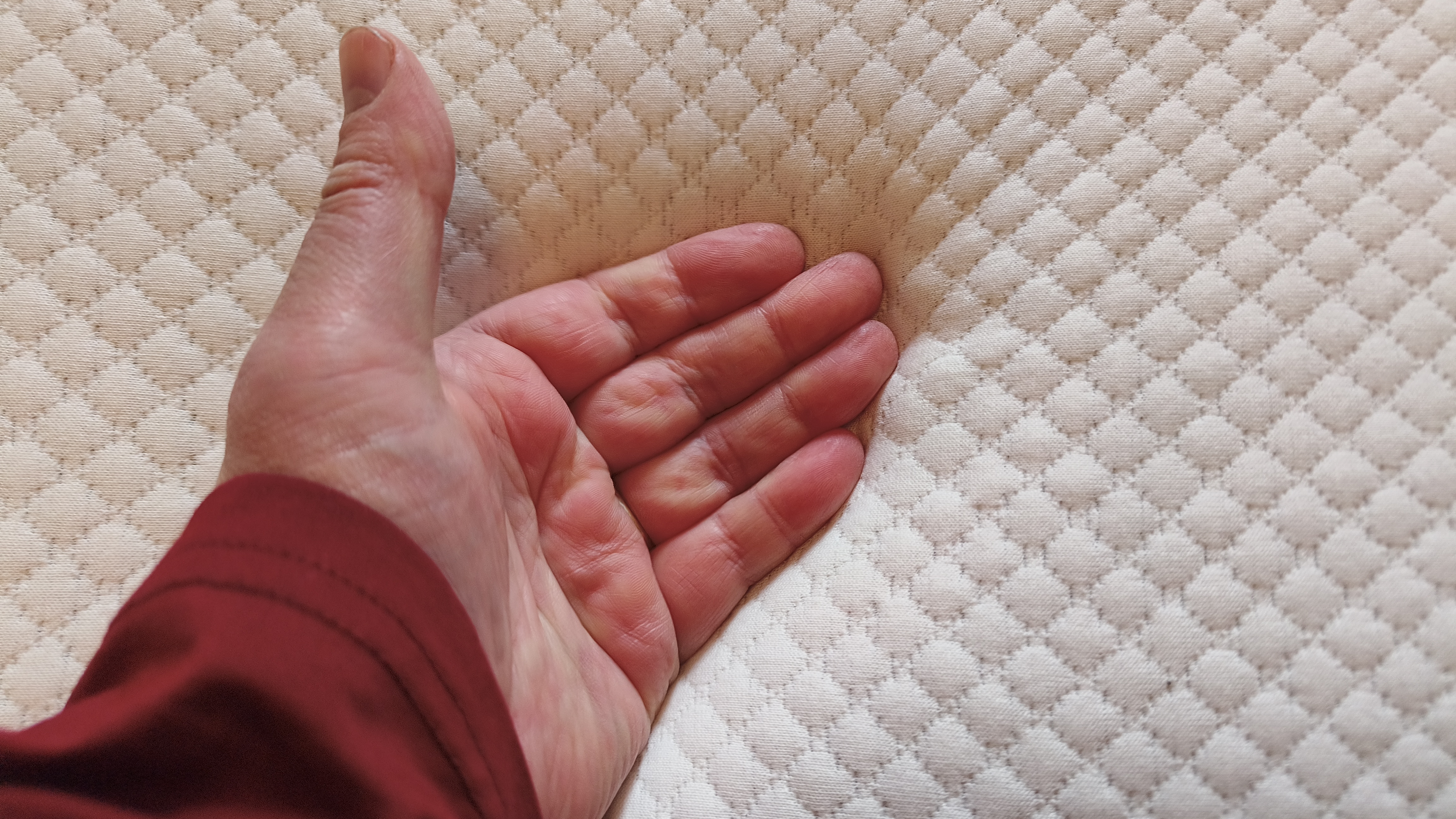 A hand held palm-down just above the surface of the Simba Cool Foam Mattress Topper to test for heat retention after prolonged contact.