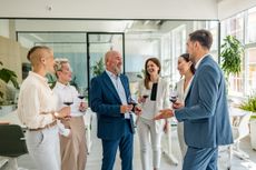 A group of colleagues enjoys a celebratory toast in a modern office setting, sharing laughter and wine as they celebrate achievements and milestones together.