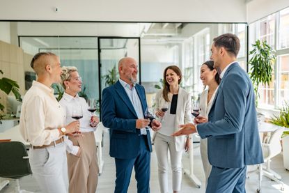 A group of colleagues enjoys a celebratory toast in a modern office setting, sharing laughter and wine as they celebrate achievements and milestones together.