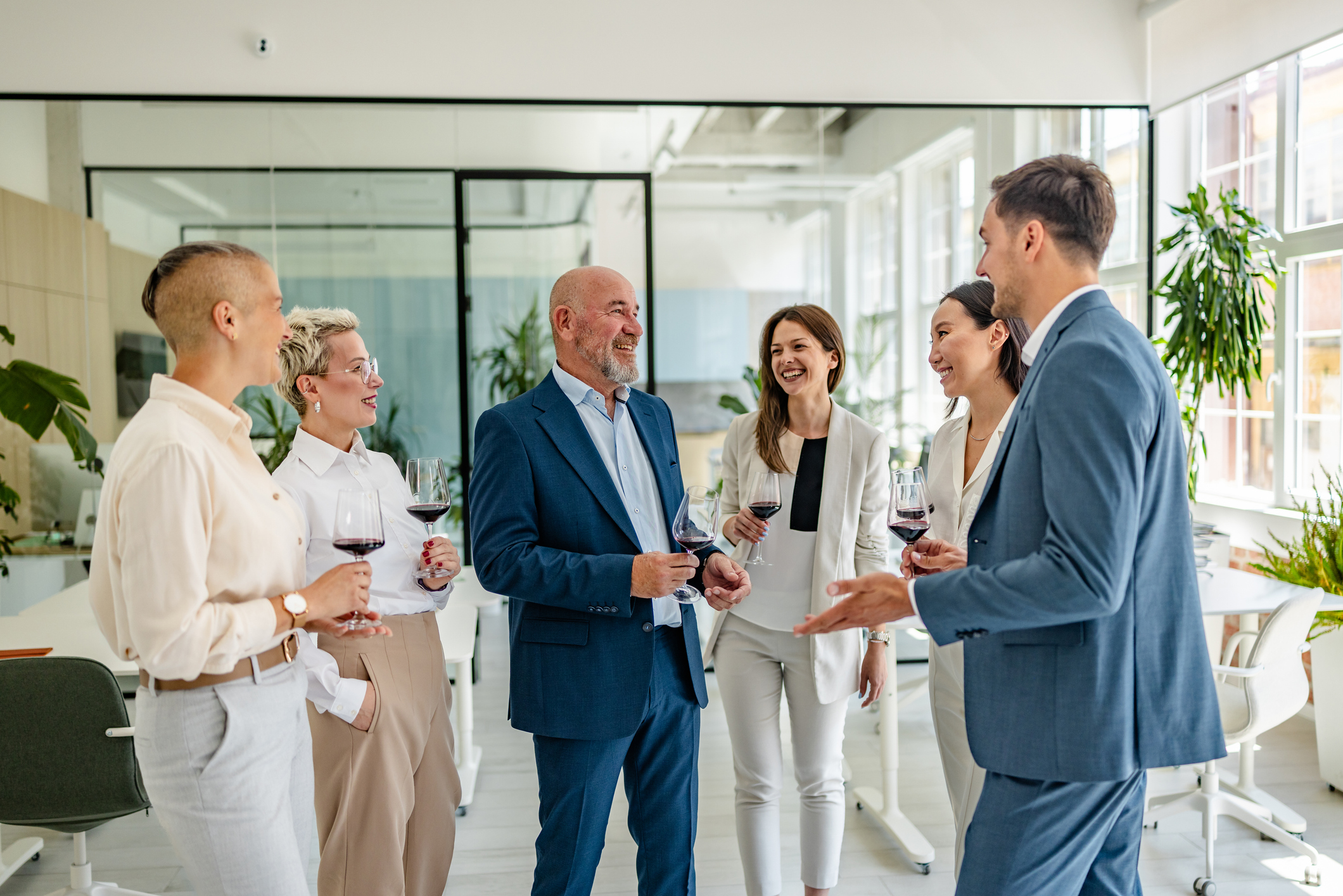 A group of colleagues enjoys a celebratory toast in a modern office setting, sharing laughter and wine as they celebrate achievements and milestones together.