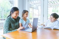 Native American teacher helps girl with a school assignment online