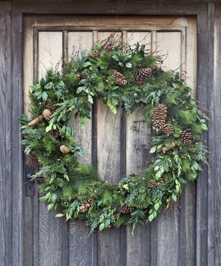 Foliage wreath on wooden door with pine cone decorations