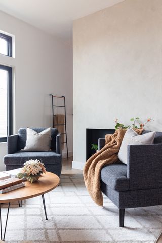 A small lounge area with two armchairs, round coffee table with hairpin leg decor and ladder shelf in background