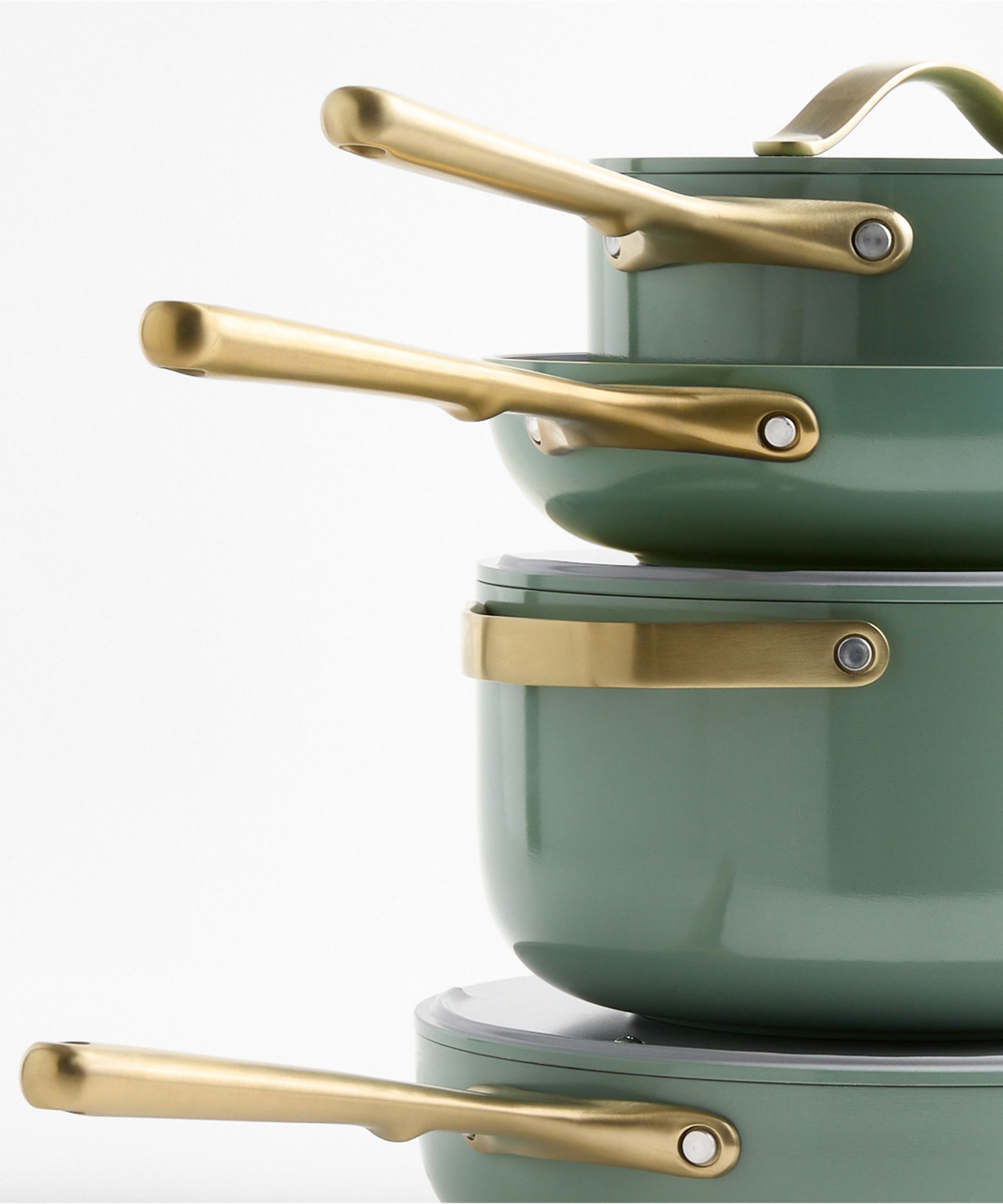 A stack of light sage green pans with brushed gold handles