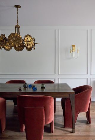 A dining room with burgundy chairs and white walls