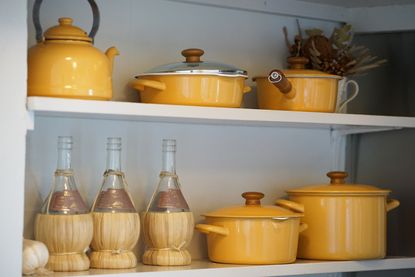 Yellow cast iron cookware set on a kitchen shelf