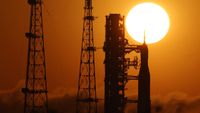 A photo of the sun rising above the Artemis II Space Launch System rocket and Orion spacecraft at Kennedy Space Center in Florida. 