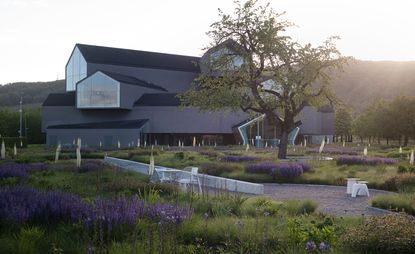 Vitra Haus, a multi-storey building part of the Vitra Campus in Weil am Rhein, Germany, photographed at sunset among greenery and purple flowers, part of Piet Oudolf's garden design