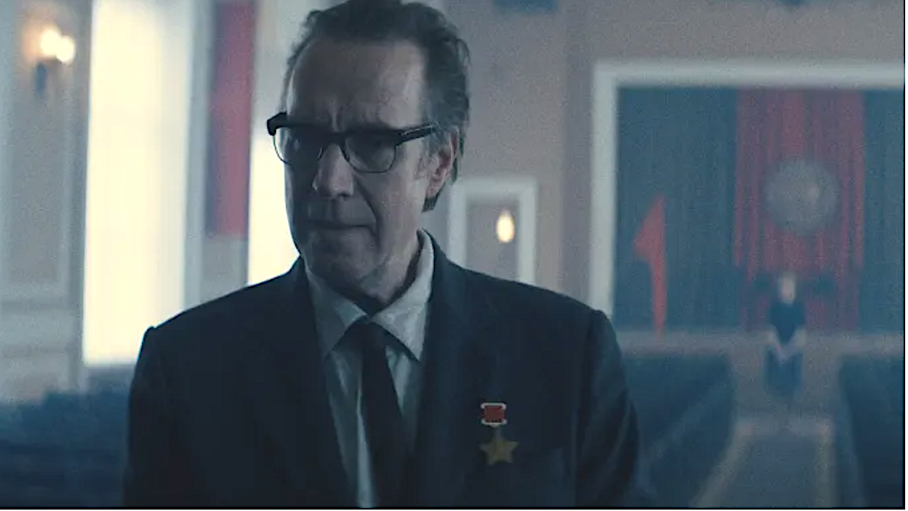 um homem de terno e óculos em um auditório