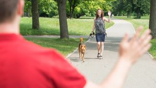 Man waving to woman walking dog in public park