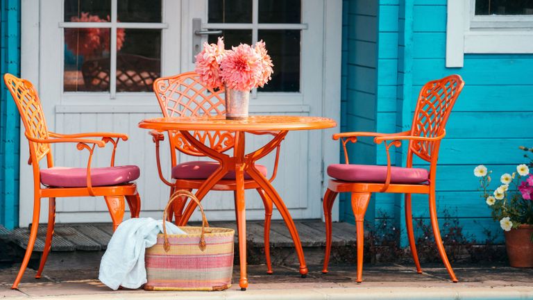 Wrought iron garden table and chairs painted in orange outdoor paint