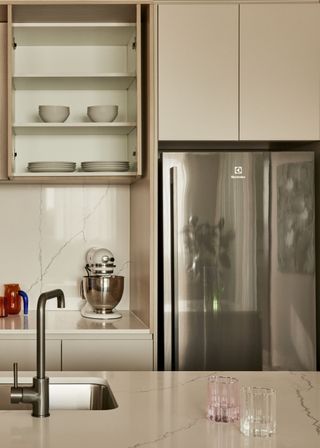 White kitchen with open cupboard and large silver fridge