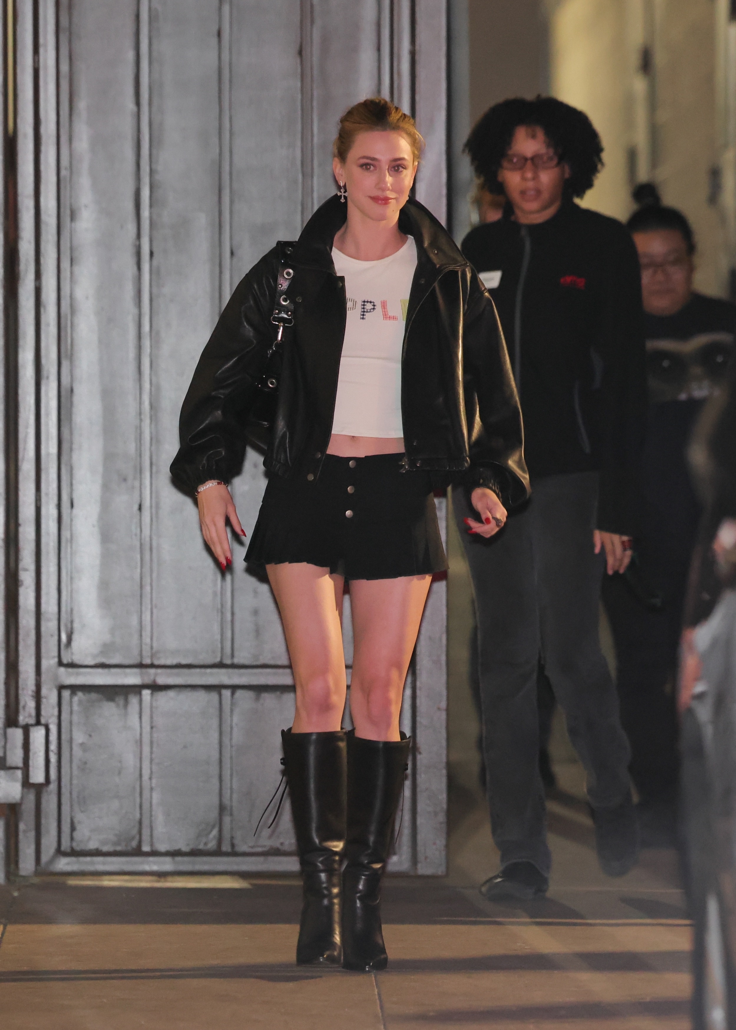 Lili Reinhart Embodies Y2K Dressing in a Black Bomber Jacket, Pleated Mini Skirt, and Edgy Black Boots