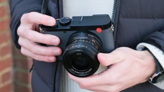 A Leica Q3 43 camera held in a pair of hands