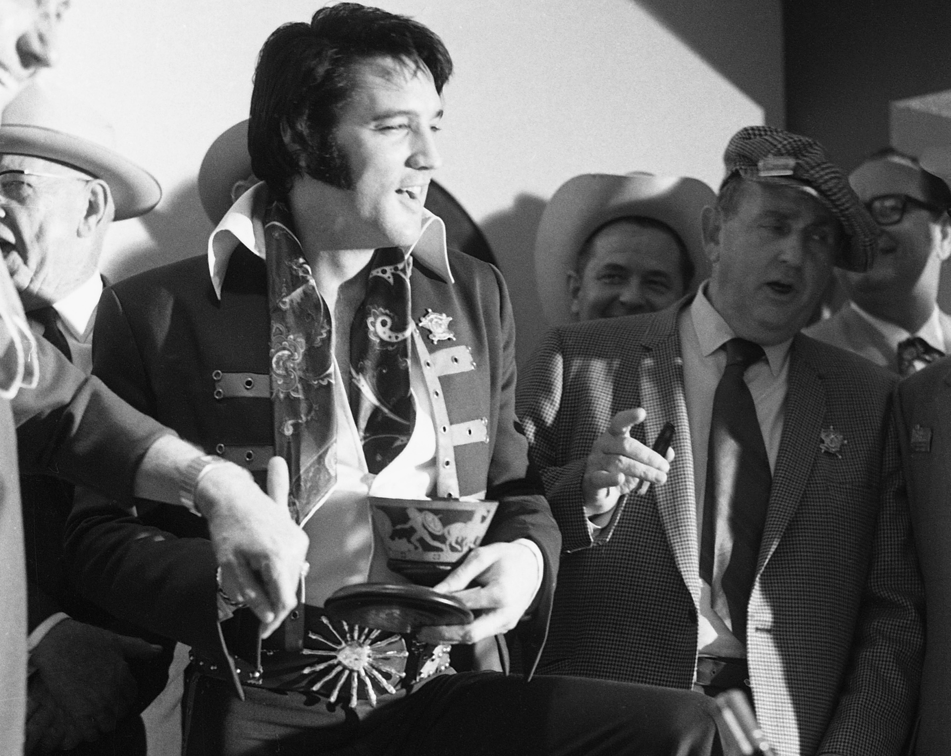 American singer Elvis Presley (1935 - 1977) is presented with a limited edition Rolex King Midas watch in a special presentation case shaped like an ancient Greek vase, for his run of concerts at the Houston Astrodome Livestock Show and Rodeo, Texas, 1st March 1970. On the right is his manager, Colonel Tom Parker (1909 - 1997). (Photo by Silver Screen Collection/Getty Images)