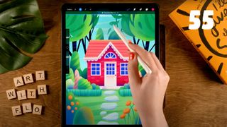 A photo of an artist drawing a colourful illustration of a house on an iPad in Procreate on a wooden desk