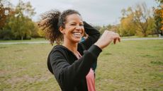 Smiling woman wearing workout clothes exercising in park, representing how to lower blood pressure quickly