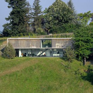 Daytime outside image of The Biscuit House by AU*M Architectes Urbanistes, green lawn, trees, blue sky