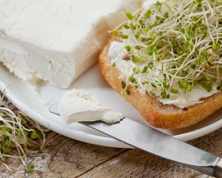 a roll with cream cheese and broccoli sprouts