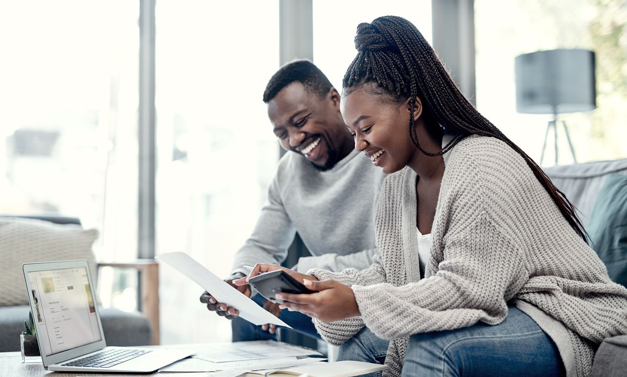 Couple smile as they look at document and laptop