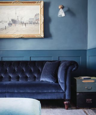 A living room wall lighting idea by Fritz Fryer with blue velvet chesterfield sofa and brass framed wall art