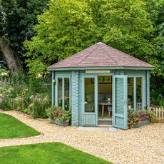 Gravel garden with blue painted shed and surrounding trees