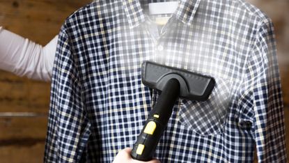 Woman ironing shirt with garment steamer