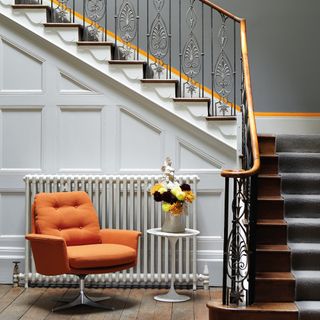 Grey hallway with panelled walls and a subtle orange stipe painted along the wall