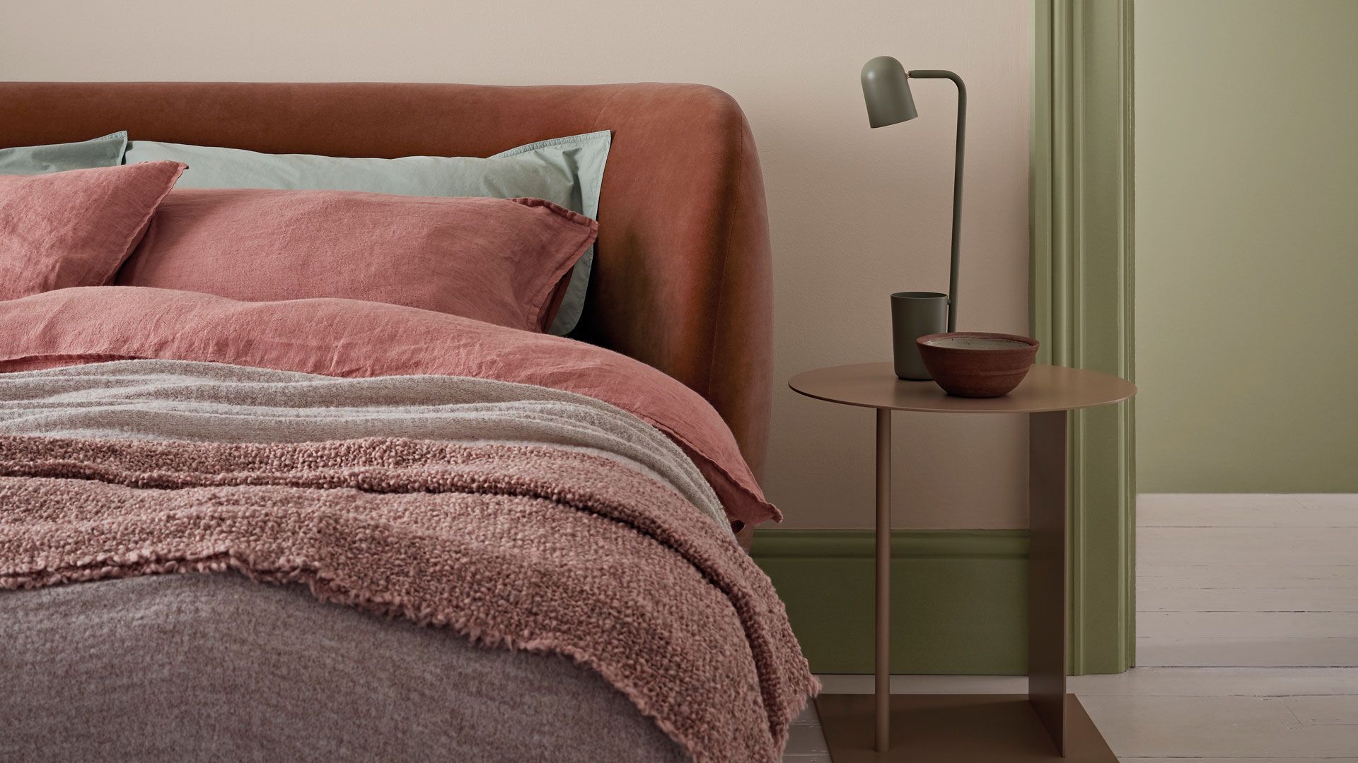 close up shot of a bed to demonstare the color drenching bedriom trend 2022 with the green painted skirting board and door frame